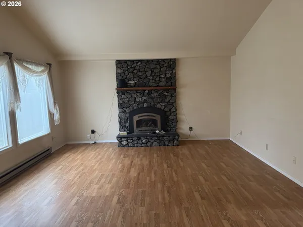 a view of empty room with wooden floor and fireplace