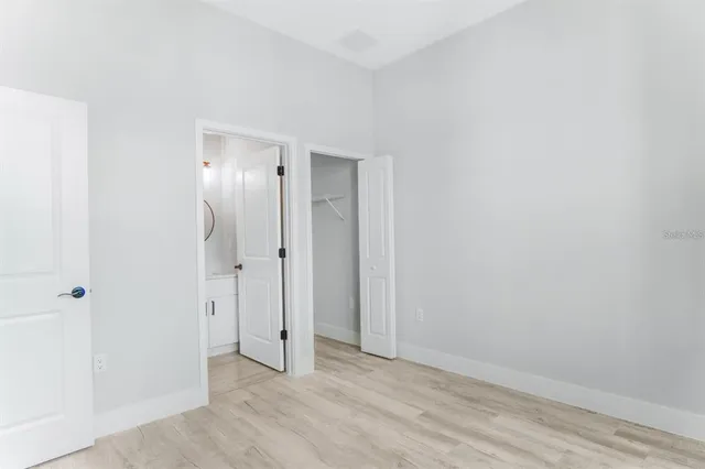 an empty room with wooden floor and a bathroom