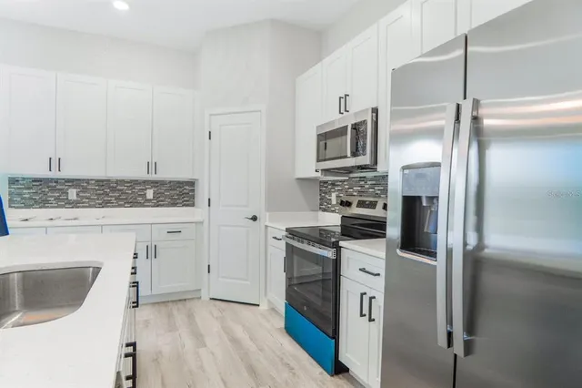 a kitchen with cabinets stainless steel appliances and wooden floor