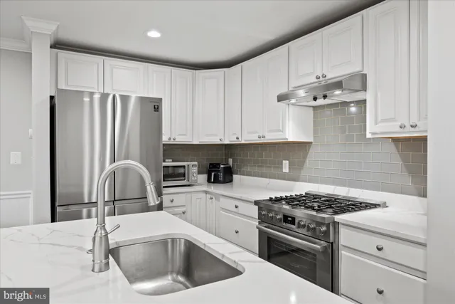 a kitchen with granite countertop a sink stainless steel appliances and cabinets