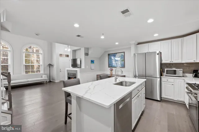 a kitchen that has a lot of cabinets a sink and wooden floor