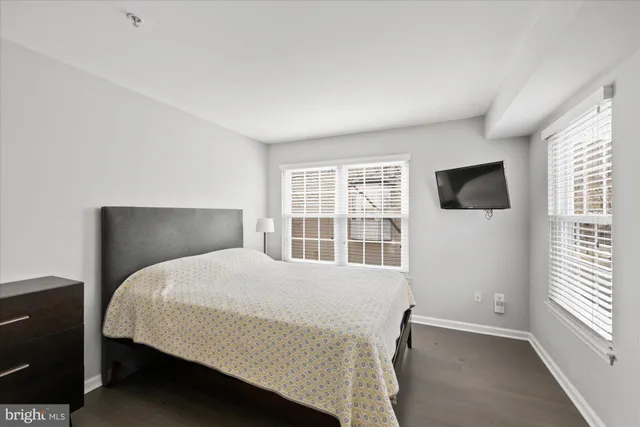 a bedroom with a bed tv and next to a window