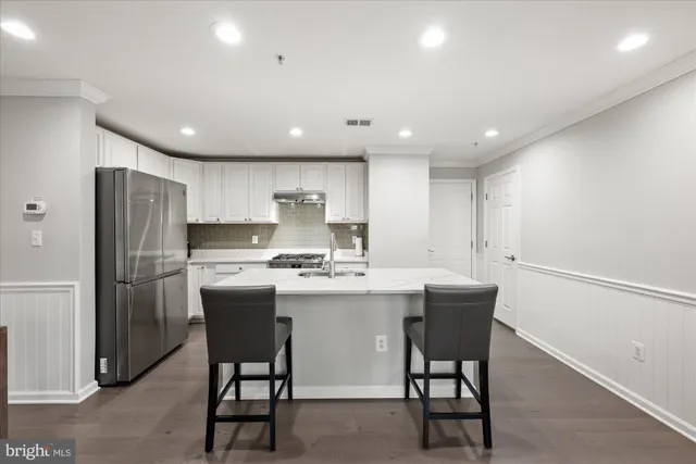 a kitchen with refrigerator and chairs