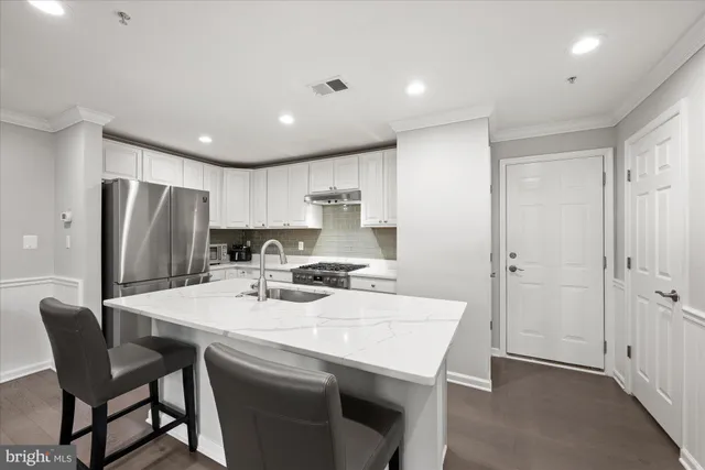 a kitchen with a dining table chairs refrigerator and cabinets
