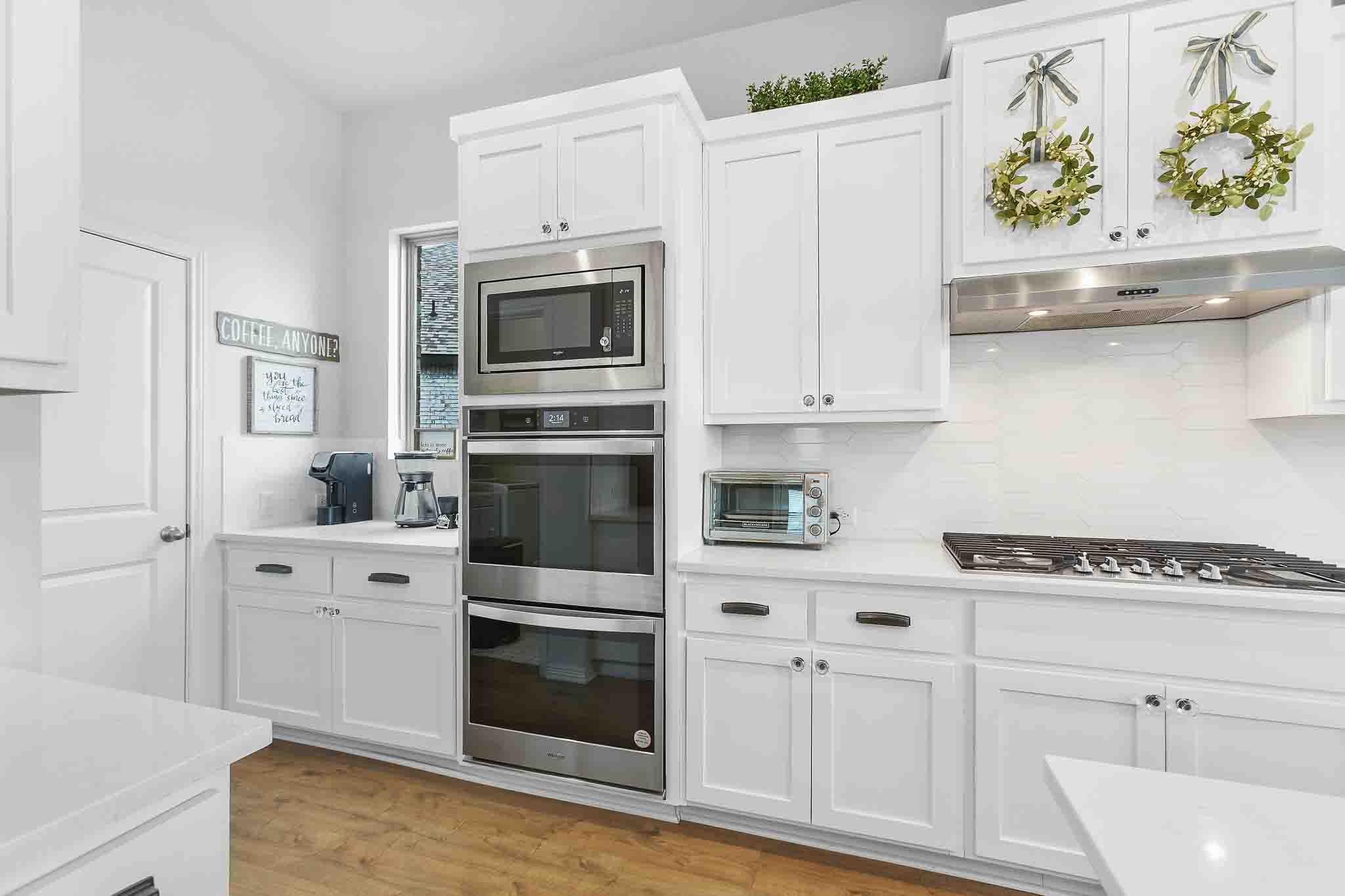 166 West Branch Road Kyle, TX 78640 - Photo 7 of 39 White cabinetry with sleek hardware and light wood flooring creates an inviting atmosphere in this well-appointed kitchen.