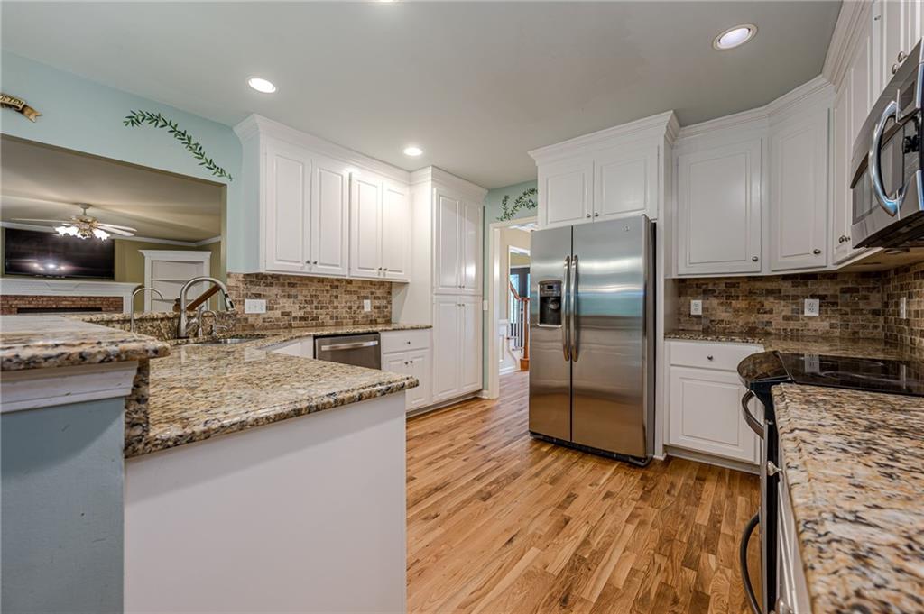 461 Braidwood Walk Northwest Acworth, GA 30101 - Photo 29 of 67 a kitchen with stainless steel appliances granite countertop a refrigerator a stove and a sink with wooden floor