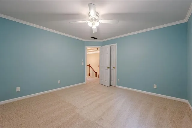 a view of an empty room with chandelier fan