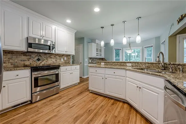 a kitchen with stainless steel appliances granite countertop a stove a sink and white cabinets