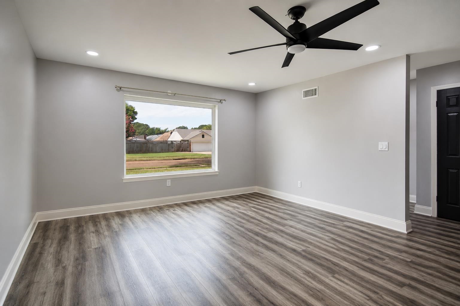 2978 Ruffle Drive Bartlett, TN 38134 - Photo 3 of 12 Spacious room featuring wood-finish flooring, a large window, a ceiling fan, recessed lighting, and a paneled door