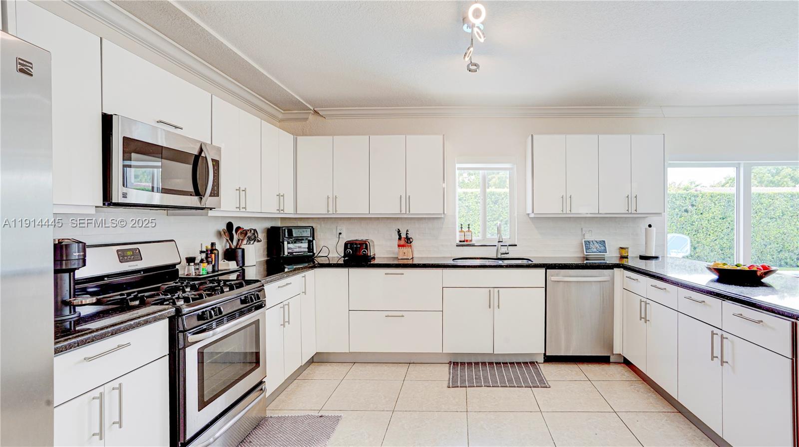 9573 Southwest 57th Street Miami, FL 33173 - Photo 9 of 34 a white kitchen with stainless steel appliances granite countertop a stove a sink and white cabinets