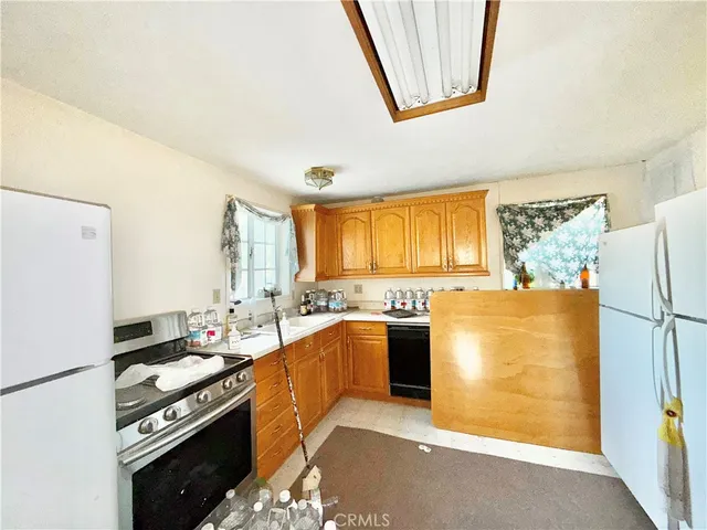 a kitchen with stainless steel appliances granite countertop a stove a refrigerator a sink dishwasher and a stove with wooden floor