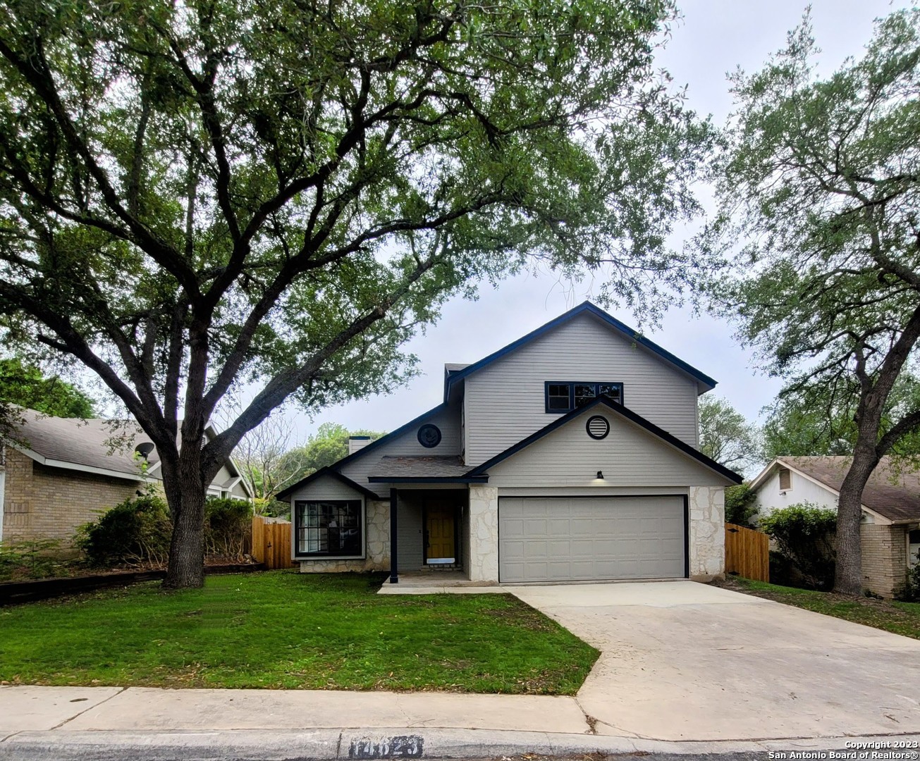 a front view of a house with a garden and trees