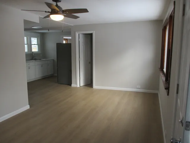 an empty room with wooden floor and a ceiling fan