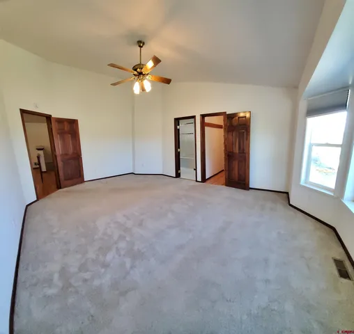 an empty room with chandelier fan and windows