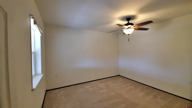 an empty room with closet and a chandelier fan