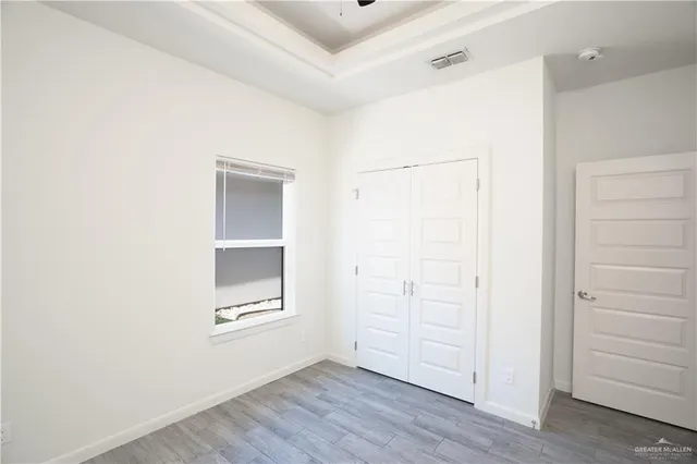 a view of an empty room with closet and wooden floor