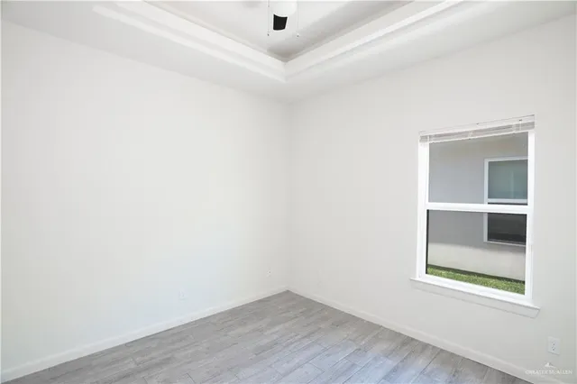 a view of an empty room with a window and wooden floor