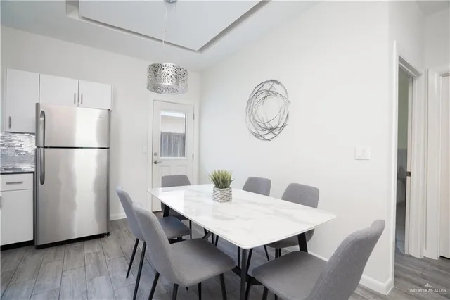 a view of a dining room with furniture a refrigerator and wooden floor