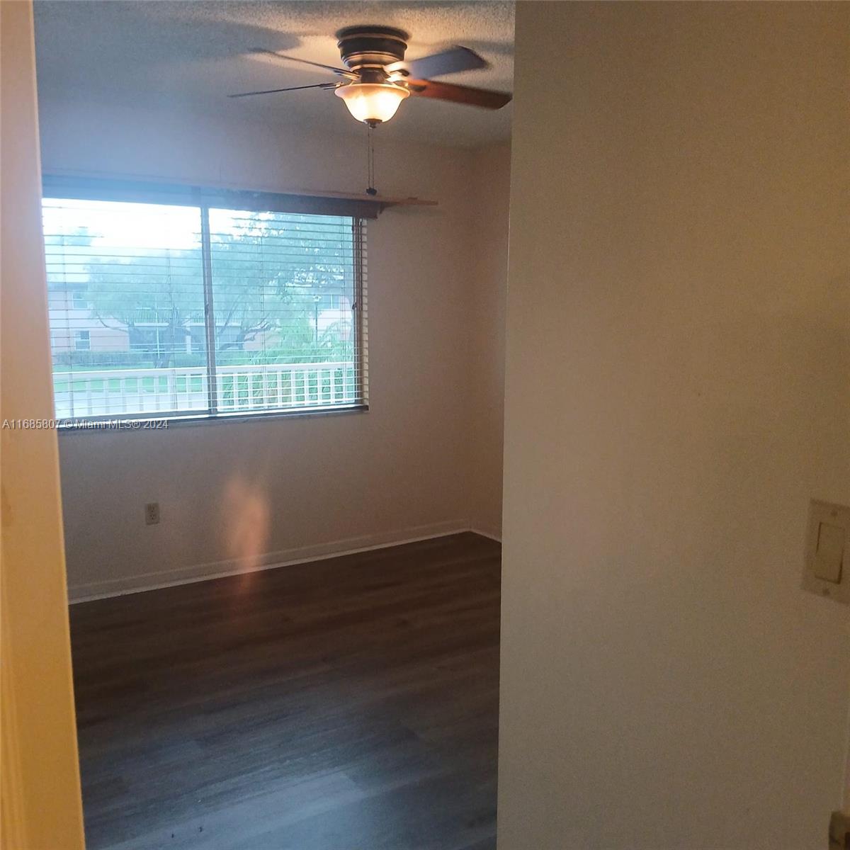 7136 South Devon Drive, Unit 207 Tamarac, FL 33321 - Photo 12 of 24 an empty room with wooden floor and windows