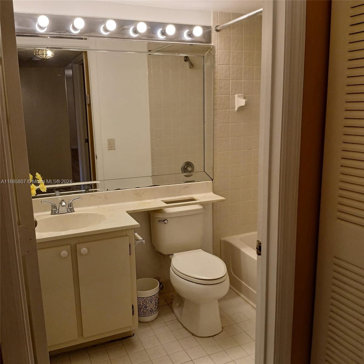 7136 South Devon Drive, Unit 207 Tamarac, FL 33321 - Photo 13 of 24 a bathroom with a toilet a sink and mirror