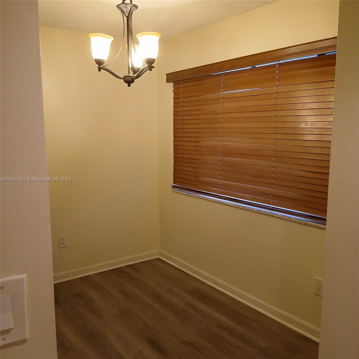 7136 South Devon Drive, Unit 207 Tamarac, FL 33321 - Photo 10 of 24 a view of a hallway with wooden floor and chandelier
