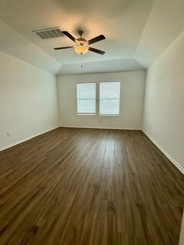 an empty room with wooden floor fan and windows