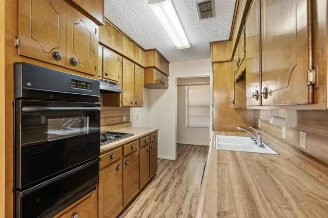 a kitchen that has a sink a stove and a wooden floor