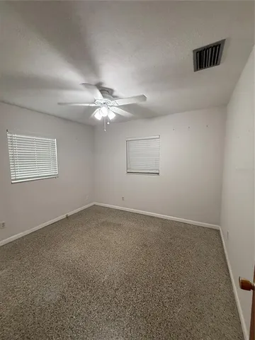 an empty room with a chandelier fan and windows
