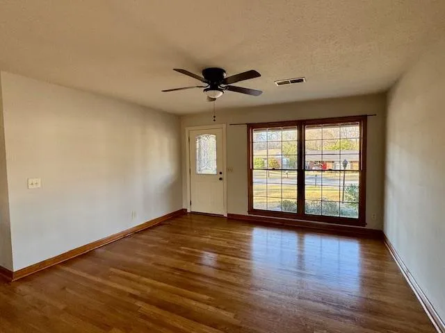 a view of an empty room with window and wooden floor