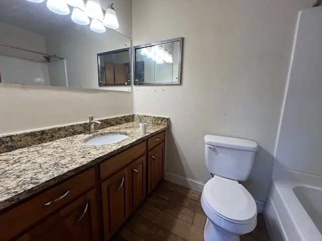 a bathroom with a granite countertop toilet sink and mirror