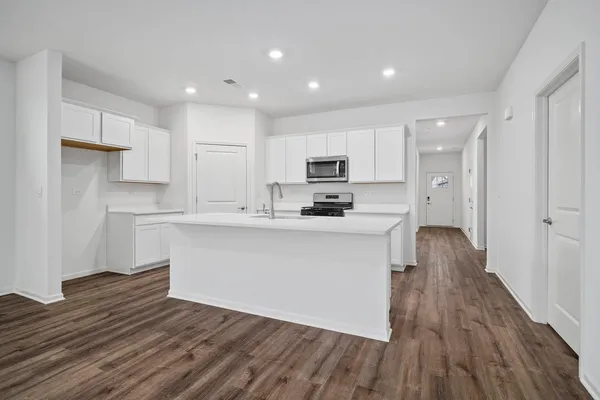 a kitchen with wooden floors white cabinets and stainless steel appliances