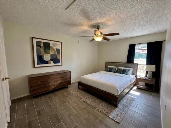 a bedroom with a bed ceiling fan and a wooden floor