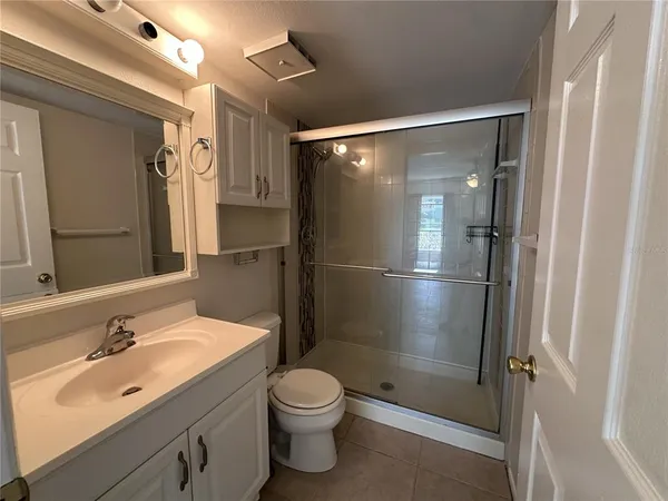 a bathroom with a shower sink vanity mirror and toilet