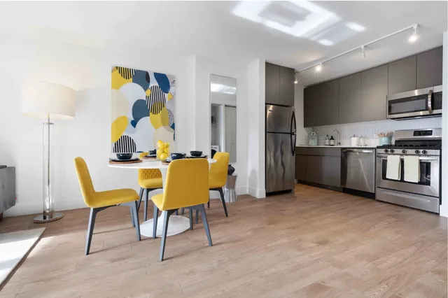 a living room with stainless steel appliances furniture and a kitchen view