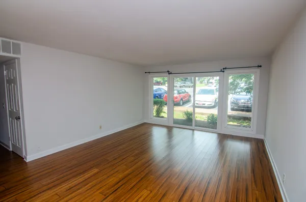 a view of an empty room with wooden floor and a window