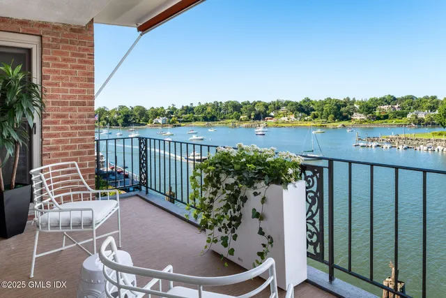 a view of a balcony with wooden chairs and floor to ceiling window