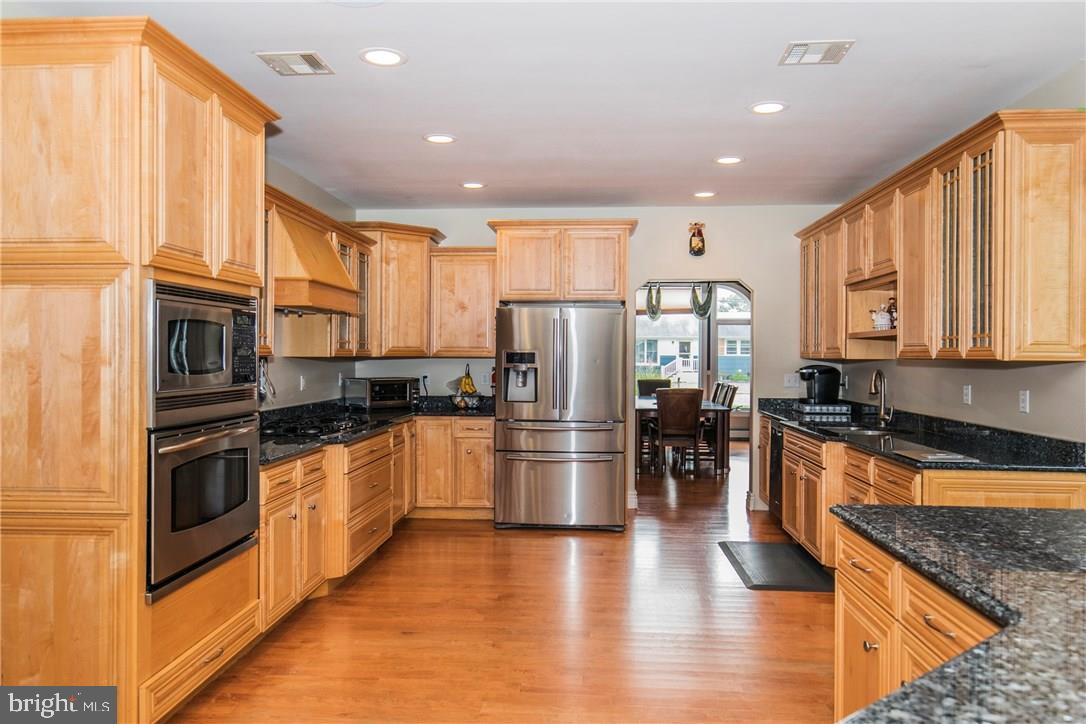 39 Harbor Inn Road Bayville, NJ 08721 - Photo 6 of 27 a kitchen with stainless steel appliances granite countertop a refrigerator oven a sink dishwasher and white cabinets with wooden floor