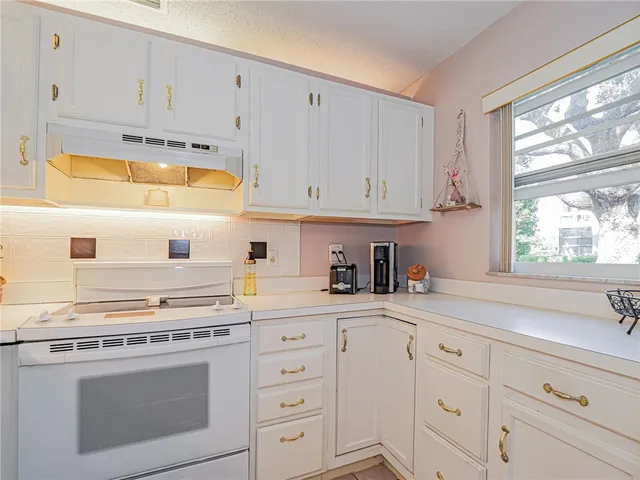 a kitchen with granite countertop white cabinets and white appliances