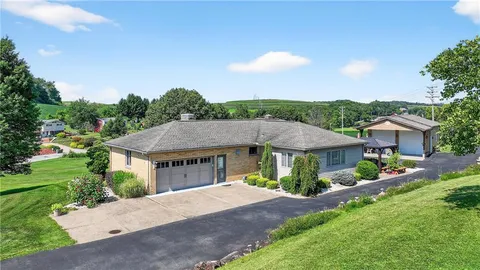 a view of a house with a yard plants and large tree