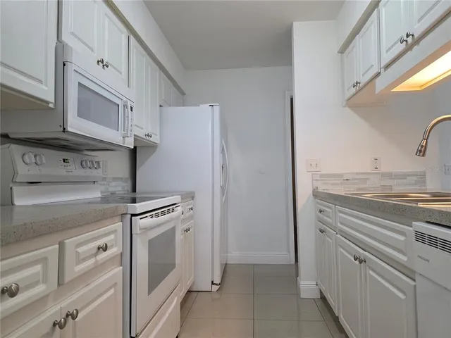 a kitchen with white cabinets and white appliances