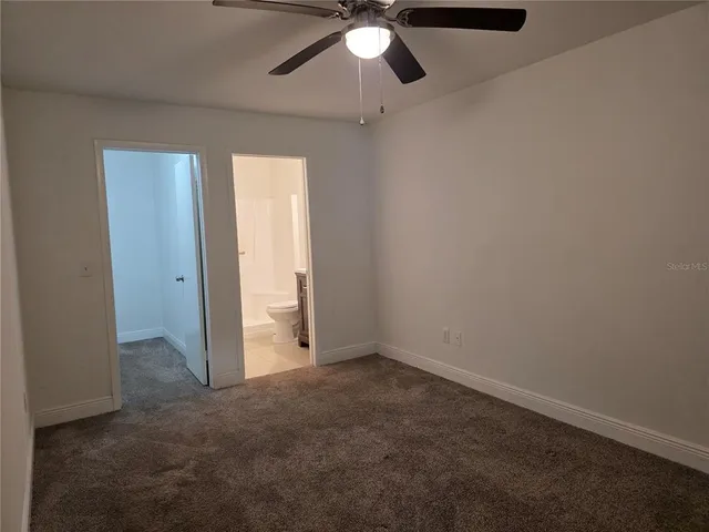 an empty room with a ceiling fan and a window