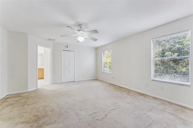 an empty room with windows and fan