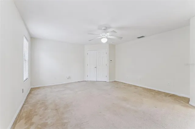 an empty room with a chandelier fan and a view of bathroom