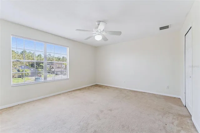an empty room with a ceiling fan and a window