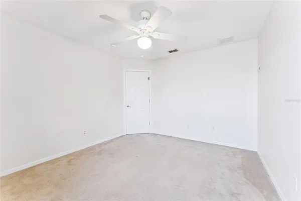 an empty room with windows and fan