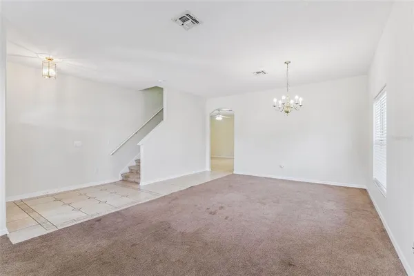 an empty room with chandelier fan and windows