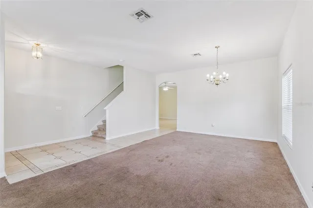 an empty room with chandelier fan and windows