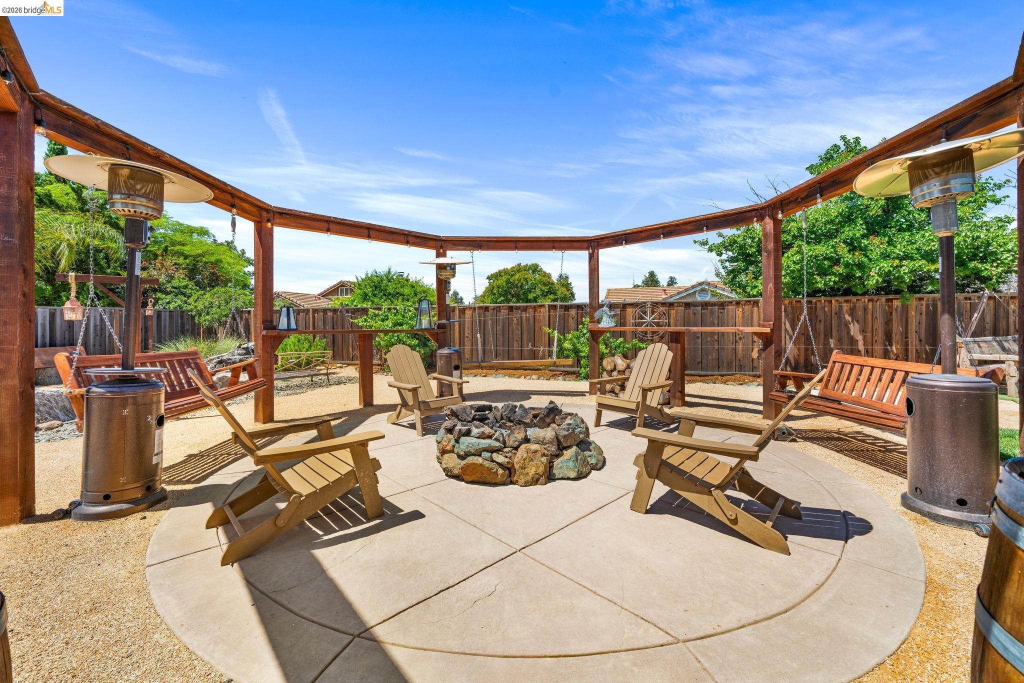 1186 El Rio Court Livermore, CA 94551 - Photo 27 of 60 Outdoor patio area featuring a circular concrete pad, a central rock fire pit, and a surrounding gravel surface