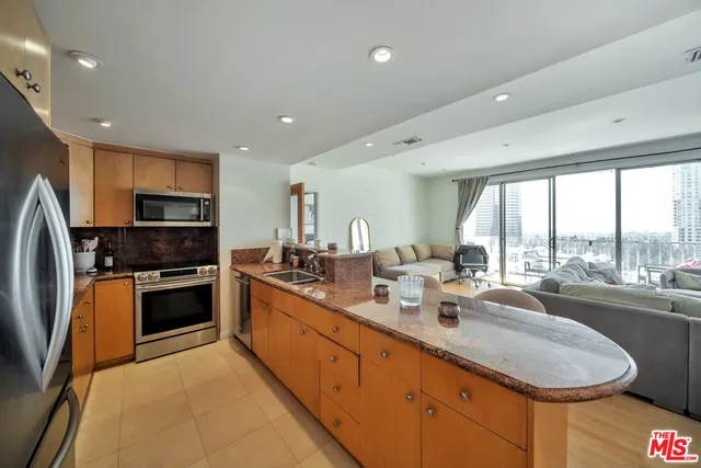 a large kitchen with kitchen island granite countertop a large window and stainless steel appliances