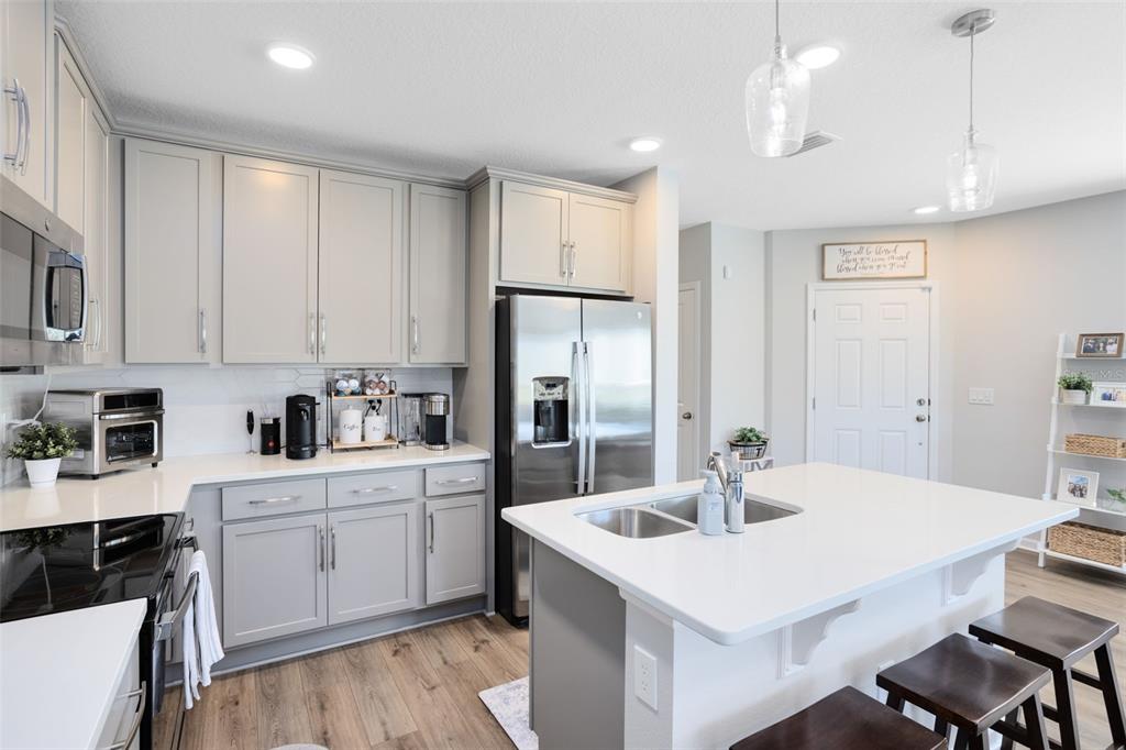 4394 Campsite Loop Orlando, FL 32824 - Photo 10 of 40 a kitchen with a sink dishwasher a stove a refrigerator and white cabinets with wooden floor